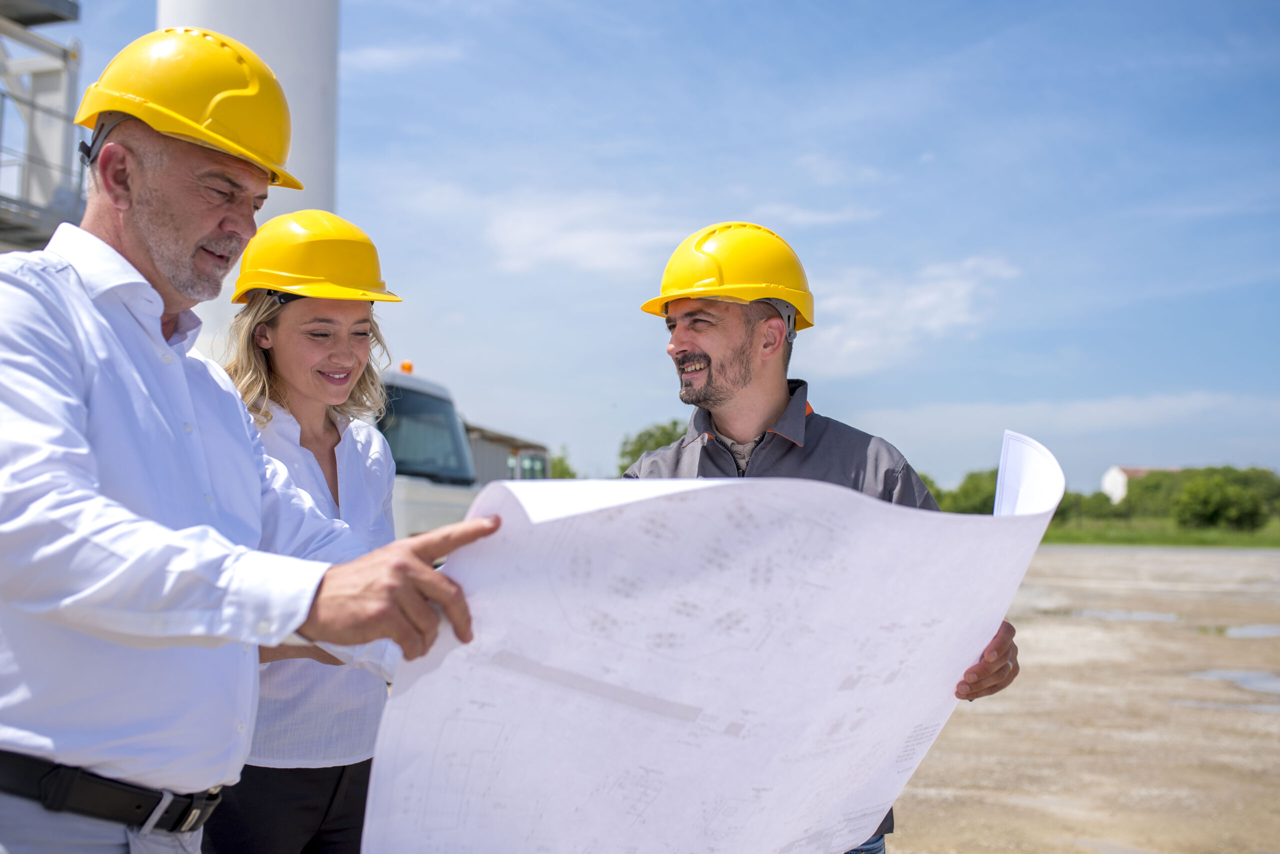 A group of construction workers looking at the plans and documents under the sunlight