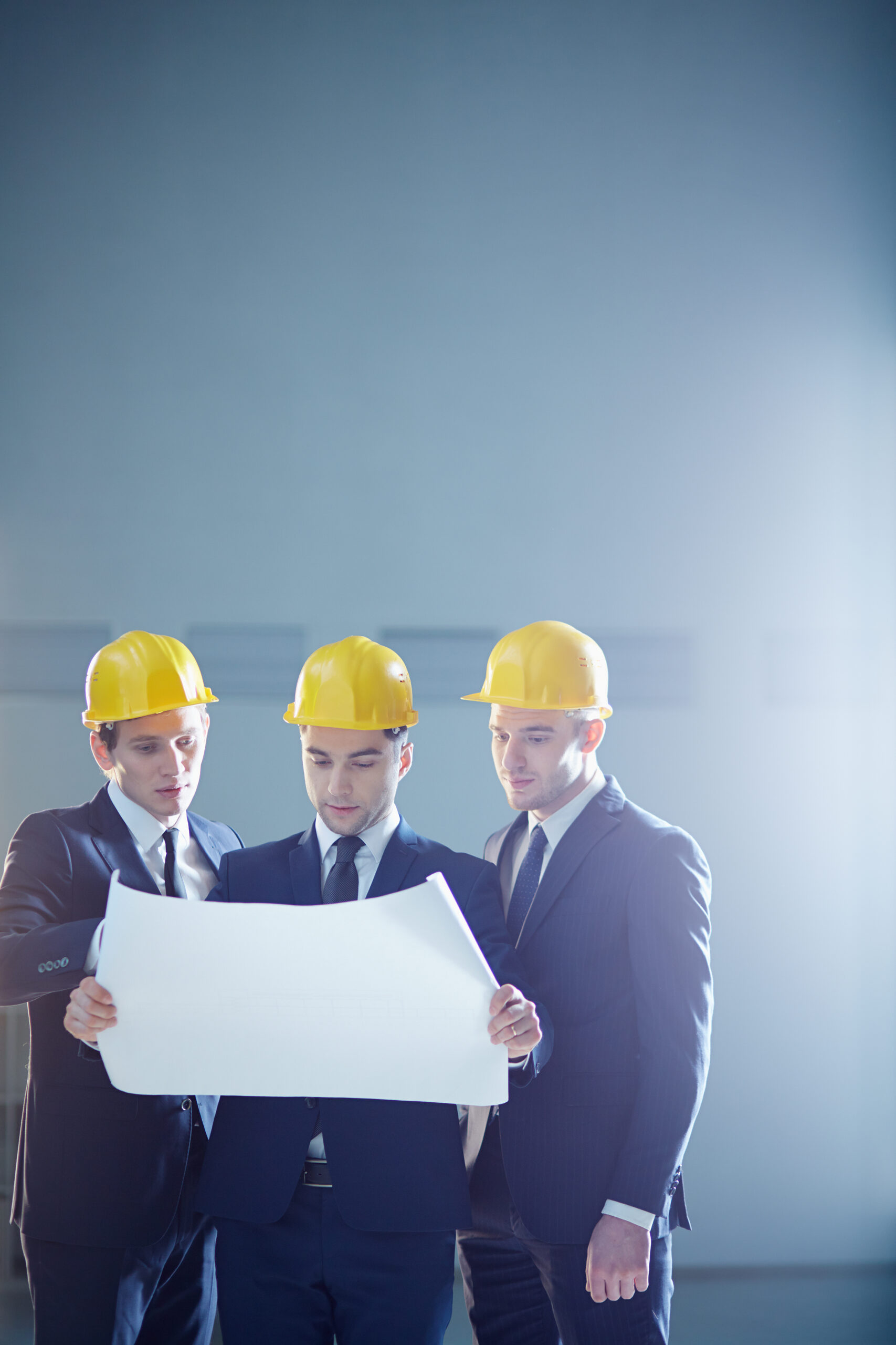 Copy-spaced image of a three construction workers holding a draft and discussing something